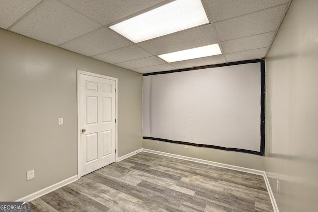 cinema room with wood finished floors, a paneled ceiling, and baseboards