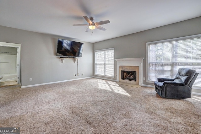 carpeted living room featuring a fireplace with flush hearth, ceiling fan, and baseboards