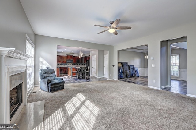carpeted living room with a high end fireplace, ceiling fan, and baseboards