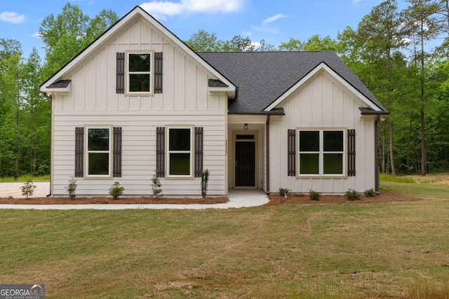 modern farmhouse featuring a front yard, a shingled roof, and board and batten siding