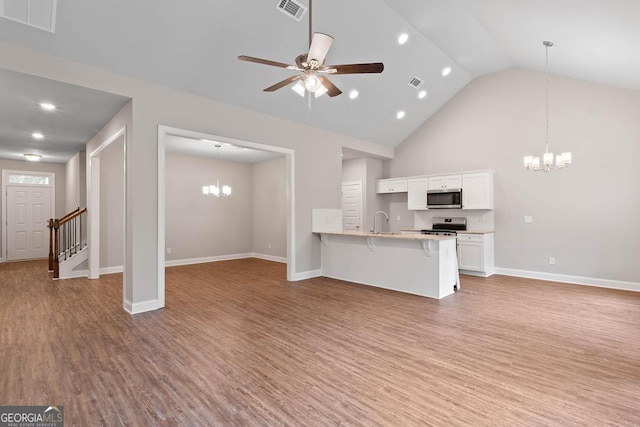 unfurnished living room with visible vents, ceiling fan with notable chandelier, light wood finished floors, and a sink