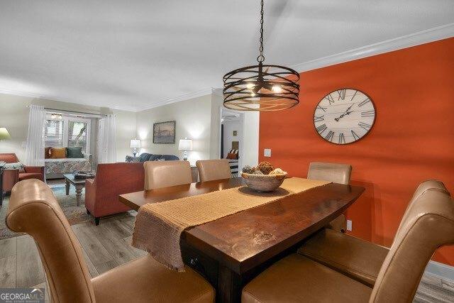 2508 Demere Rd Unit 2, Saint Simons, GA 31522 - dining room featuring a chandelier, wood finished floors, and ornamental molding