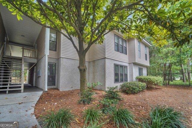 2508 Demere Rd Unit 2, Saint Simons, GA 31522 - view of property exterior featuring fence, stucco siding, and stairs
