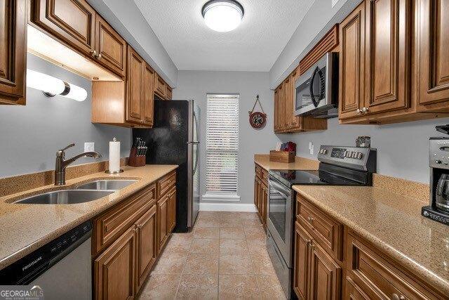 2508 Demere Rd Unit 2, Saint Simons, GA 31522 - kitchen featuring a sink, brown cabinets, stainless steel appliances, light countertops, and a textured ceiling