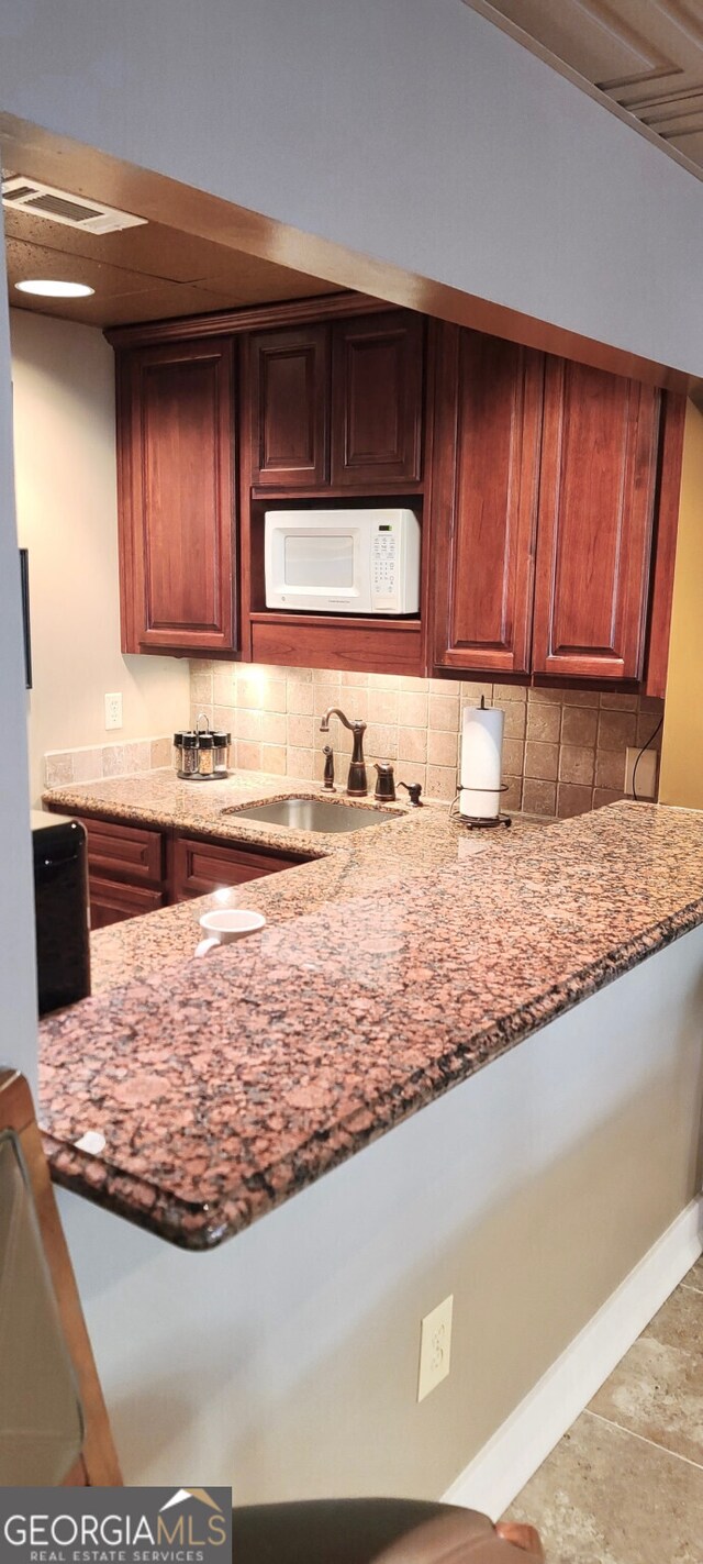 4614 Capers Xing W, Peachtree Corners, GA 30092 - kitchen with backsplash, visible vents, light stone countertops, a sink, and white microwave