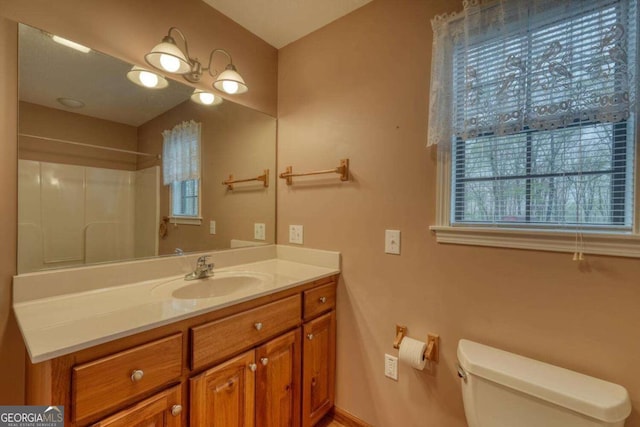 bathroom with toilet, a shower, and vanity