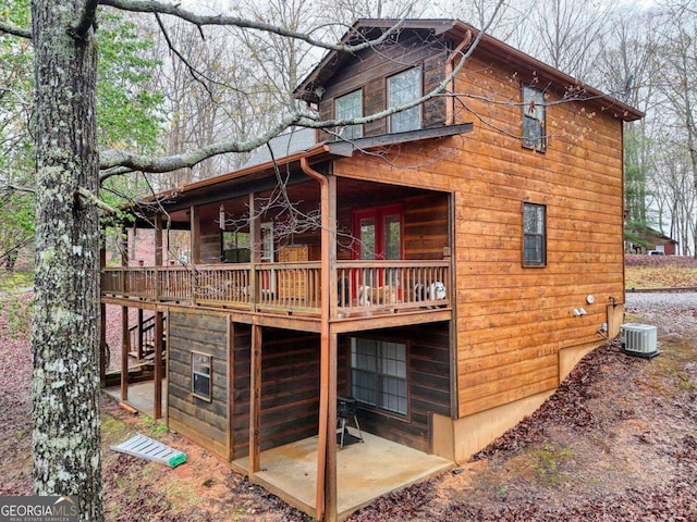 rear view of house featuring a wooden deck, central AC, and a patio area