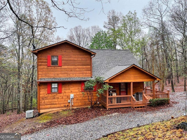 chalet / cabin featuring roof with shingles and covered porch