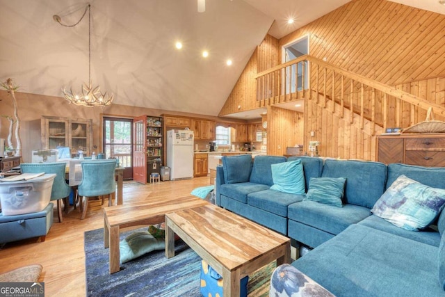 living area featuring stairway, light wood-type flooring, plenty of natural light, and high vaulted ceiling