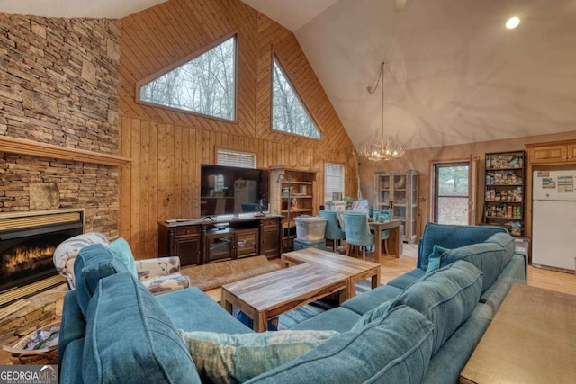 living room with an inviting chandelier, wood walls, high vaulted ceiling, and a healthy amount of sunlight