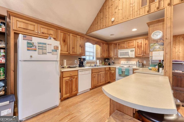 kitchen featuring light wood finished floors, white appliances, a peninsula, light countertops, and lofted ceiling