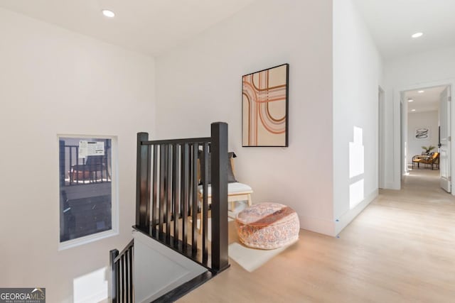 corridor featuring recessed lighting, baseboards, wood finished floors, and an upstairs landing