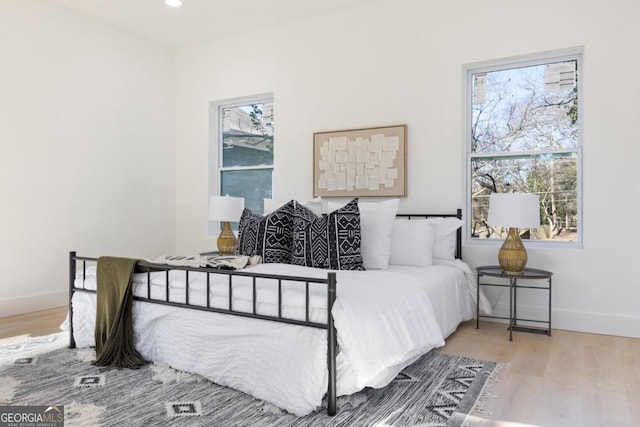 bedroom with baseboards, multiple windows, and wood finished floors