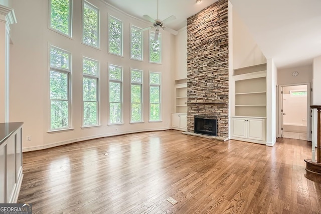 unfurnished living room with a ceiling fan, a high ceiling, a healthy amount of sunlight, and a fireplace