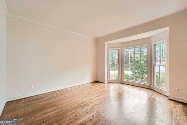 unfurnished room featuring crown molding, baseboards, and wood finished floors
