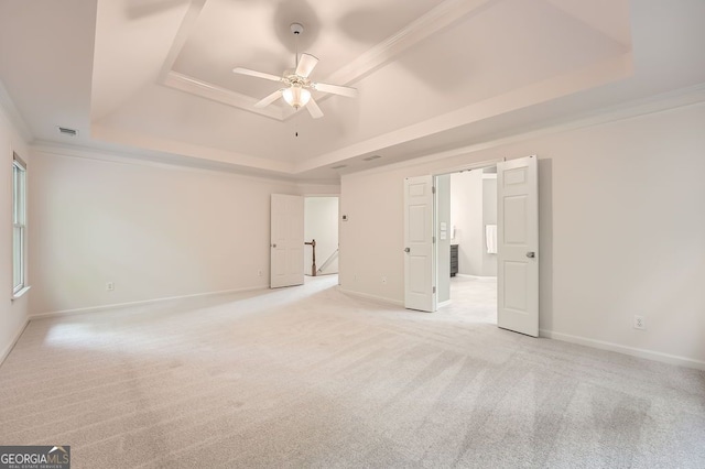 unfurnished bedroom featuring visible vents, baseboards, a tray ceiling, and light carpet