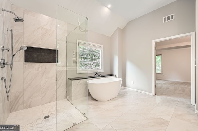 full bath with a freestanding tub, vaulted ceiling, tiled shower, and visible vents