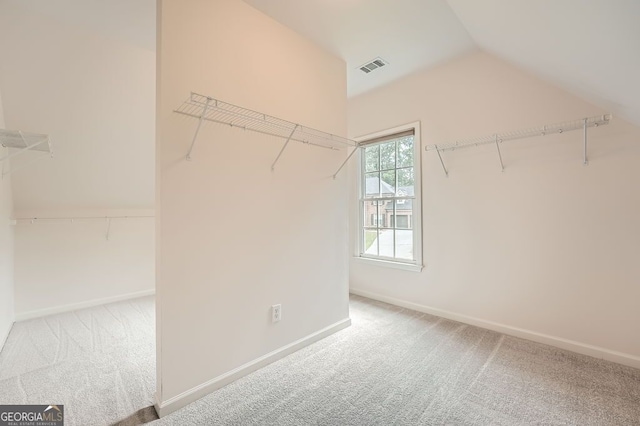 spacious closet featuring visible vents, vaulted ceiling, and carpet