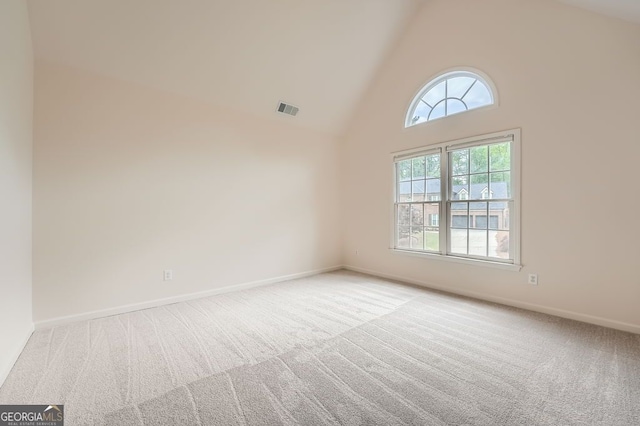 carpeted empty room featuring high vaulted ceiling, visible vents, and baseboards