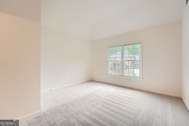 spare room featuring baseboards, carpet, vaulted ceiling, and visible vents