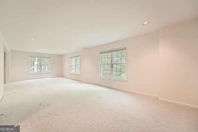 empty room featuring baseboards, recessed lighting, and light carpet