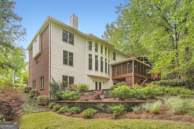 back of house with a chimney and a sunroom