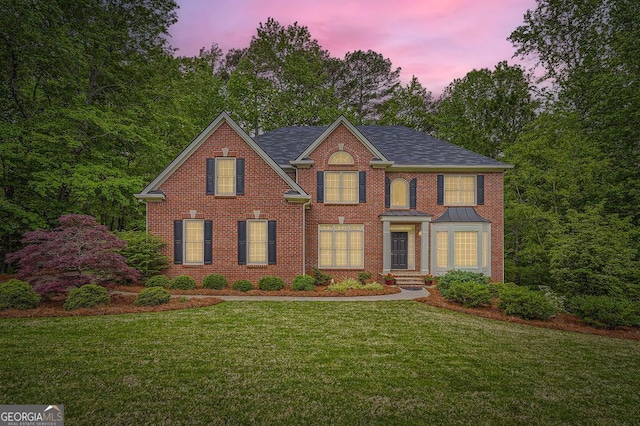 colonial home featuring a yard, brick siding, and a standing seam roof