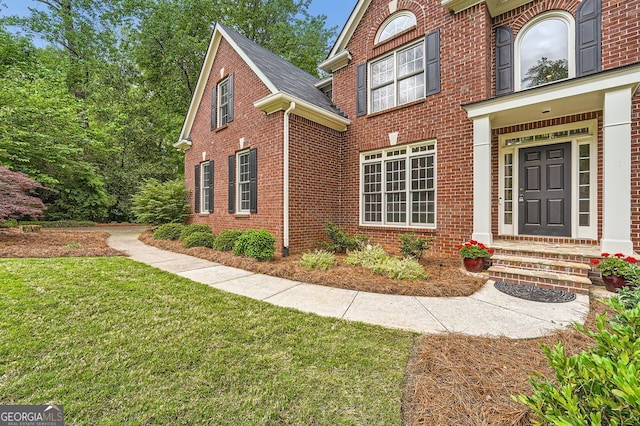 view of front of property with brick siding, a front lawn, and entry steps
