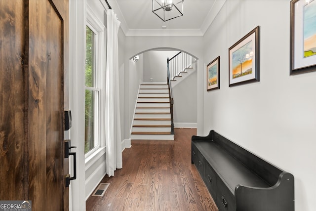 entryway featuring visible vents, crown molding, arched walkways, dark wood finished floors, and stairs