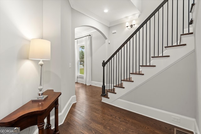 foyer with visible vents, arched walkways, wood finished floors, baseboards, and stairs