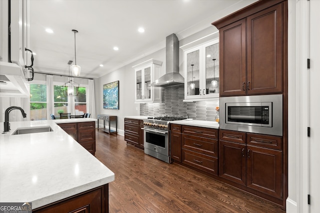 kitchen with a sink, wall chimney exhaust hood, stainless steel appliances, dark wood-type flooring, and backsplash