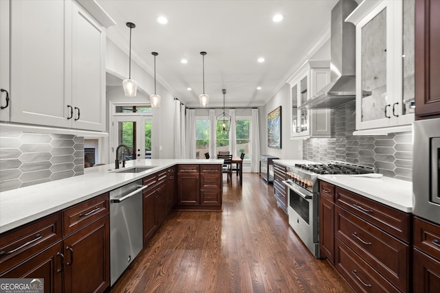 kitchen with a sink, appliances with stainless steel finishes, wall chimney range hood, and light countertops