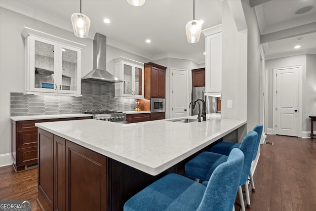 kitchen with crown molding, a sink, stainless steel microwave, and wall chimney range hood