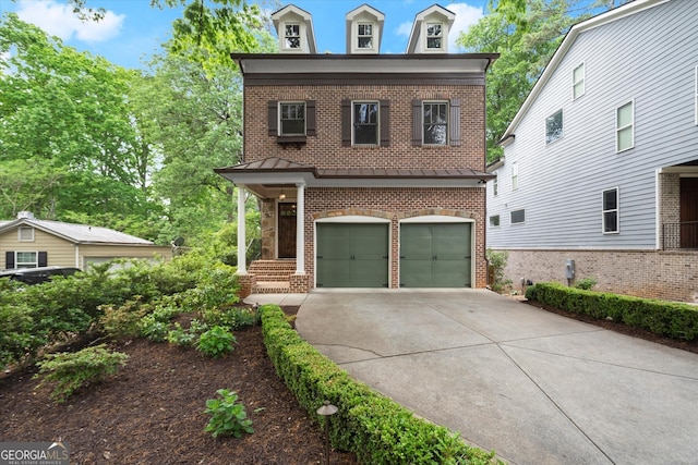 second empire-style home with concrete driveway, brick siding, and a garage