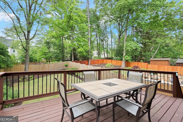 wooden terrace with a fenced backyard, outdoor dining space, and a yard