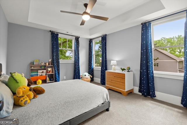 carpeted bedroom with baseboards, a ceiling fan, and a tray ceiling
