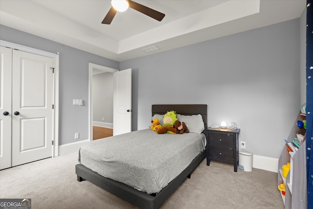 carpeted bedroom with a raised ceiling, baseboards, ceiling fan, and visible vents