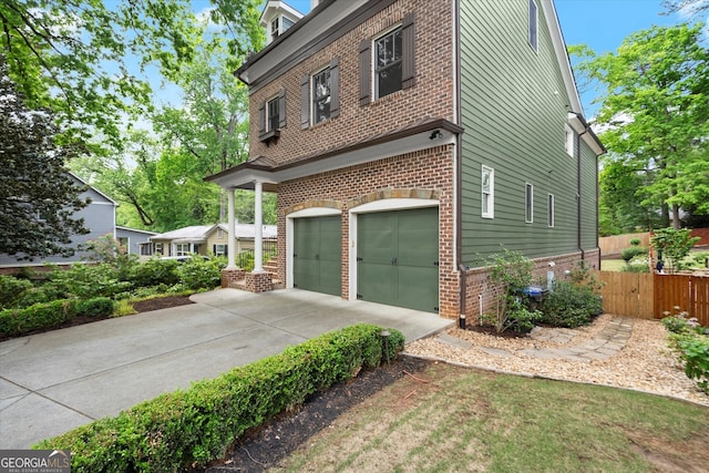view of property exterior featuring brick siding, an attached garage, fence, and concrete driveway
