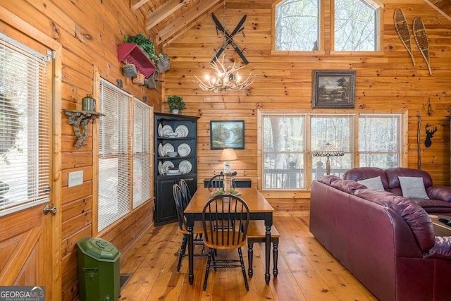 191 Mountain View Rd, Ellijay, GA 30540 - dining room featuring wood walls, light wood-type flooring, a chandelier, high vaulted ceiling, and plenty of natural light