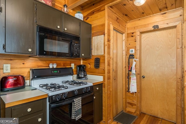 191 Mountain View Rd, Ellijay, GA 30540 - kitchen featuring range with gas cooktop, black microwave, wood walls, light countertops, and light wood-type flooring