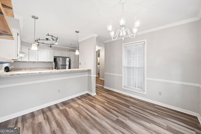 3765 Windsor Cir, Clarkston, GA 30021 - kitchen with ornamental molding, a notable chandelier, wood finished floors, and freestanding refrigerator
