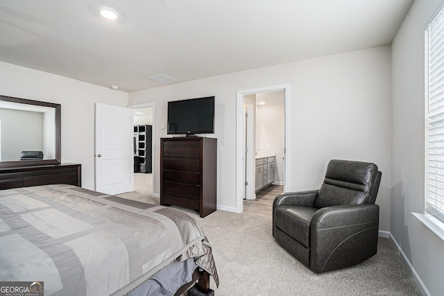 bedroom with connected bathroom, baseboards, light colored carpet, and multiple windows