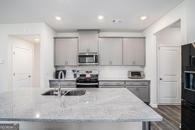 kitchen featuring gray cabinetry, stainless steel appliances, a sink, and visible vents