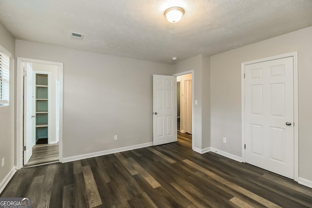 unfurnished bedroom with visible vents, dark wood finished floors, and baseboards