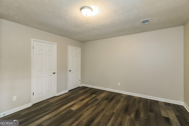 spare room with visible vents, baseboards, and dark wood finished floors