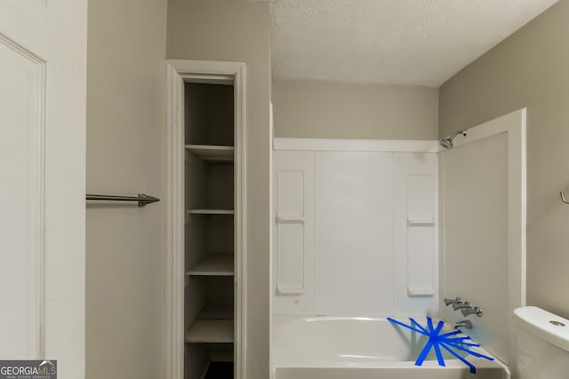 full bathroom featuring toilet, a textured ceiling, and shower / bathing tub combination