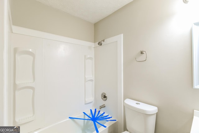 bathroom featuring a textured ceiling, toilet, and bathtub / shower combination