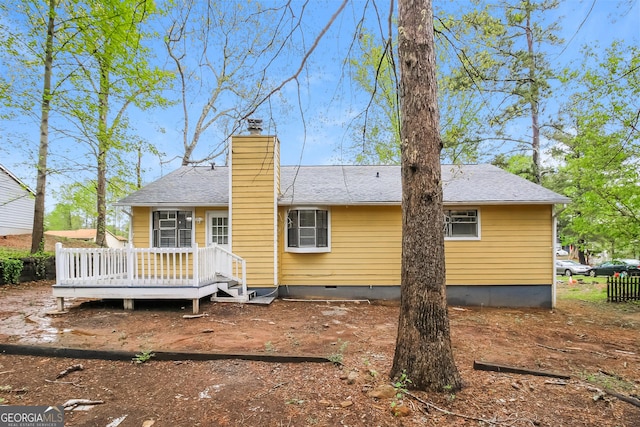back of property with a deck, a shingled roof, a chimney, and crawl space