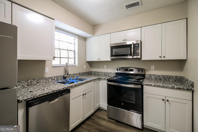 kitchen featuring a sink, dark wood-type flooring, visible vents, white cabinetry, and appliances with stainless steel finishes