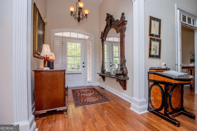 entryway featuring baseboards, wood finished floors, and a chandelier